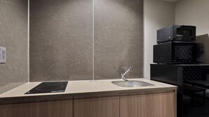 A modern kitchen with a built-in induction cooktop, a sink, and a microwave. - MONday Apart Hamamatsucho Daimon (Tokyo)