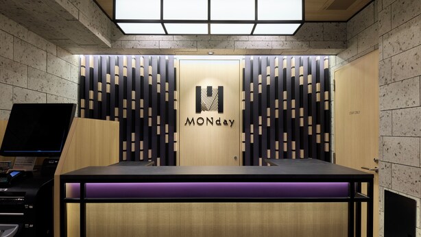 A reception desk with a 'MONday' sign, a computer monitor, and a wooden panel wall. - MONday Apart Hamamatsucho Daimon (Tokyo)