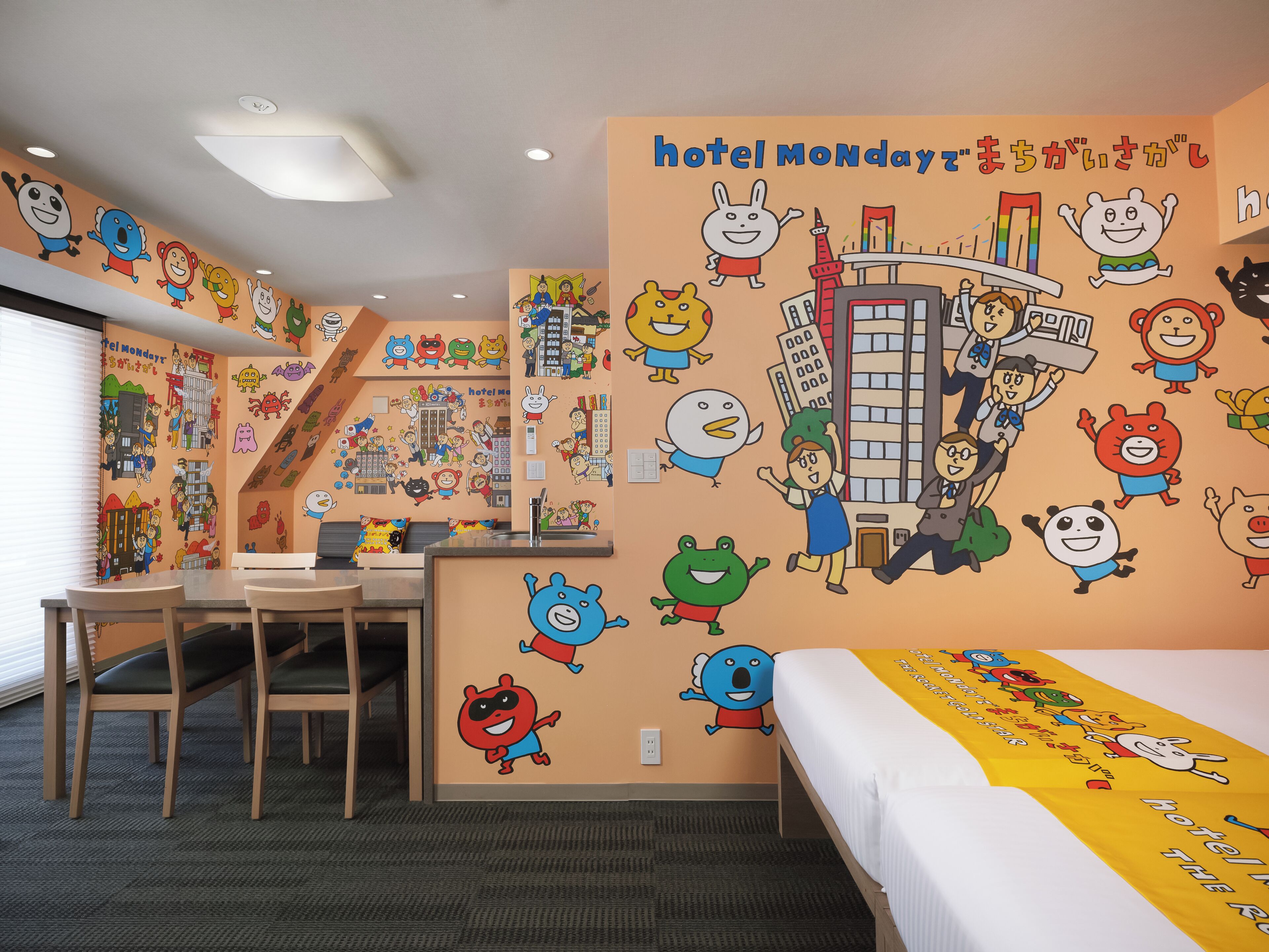 A hotel room with a bed, a desk, and a chair. The walls are decorated with cartoon characters and the words 'hotel Monday'.