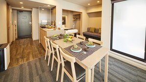 A modern hotel room with a dining area, a sofa, and a large window. - MONday Apart Premium Hamamatsucho (Tokyo)