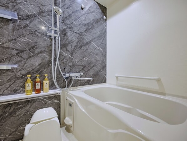 Une salle de bain avec une baignoire, des toilettes et une douche. Il y a trois flacons de produits de toilette sur le comptoir.