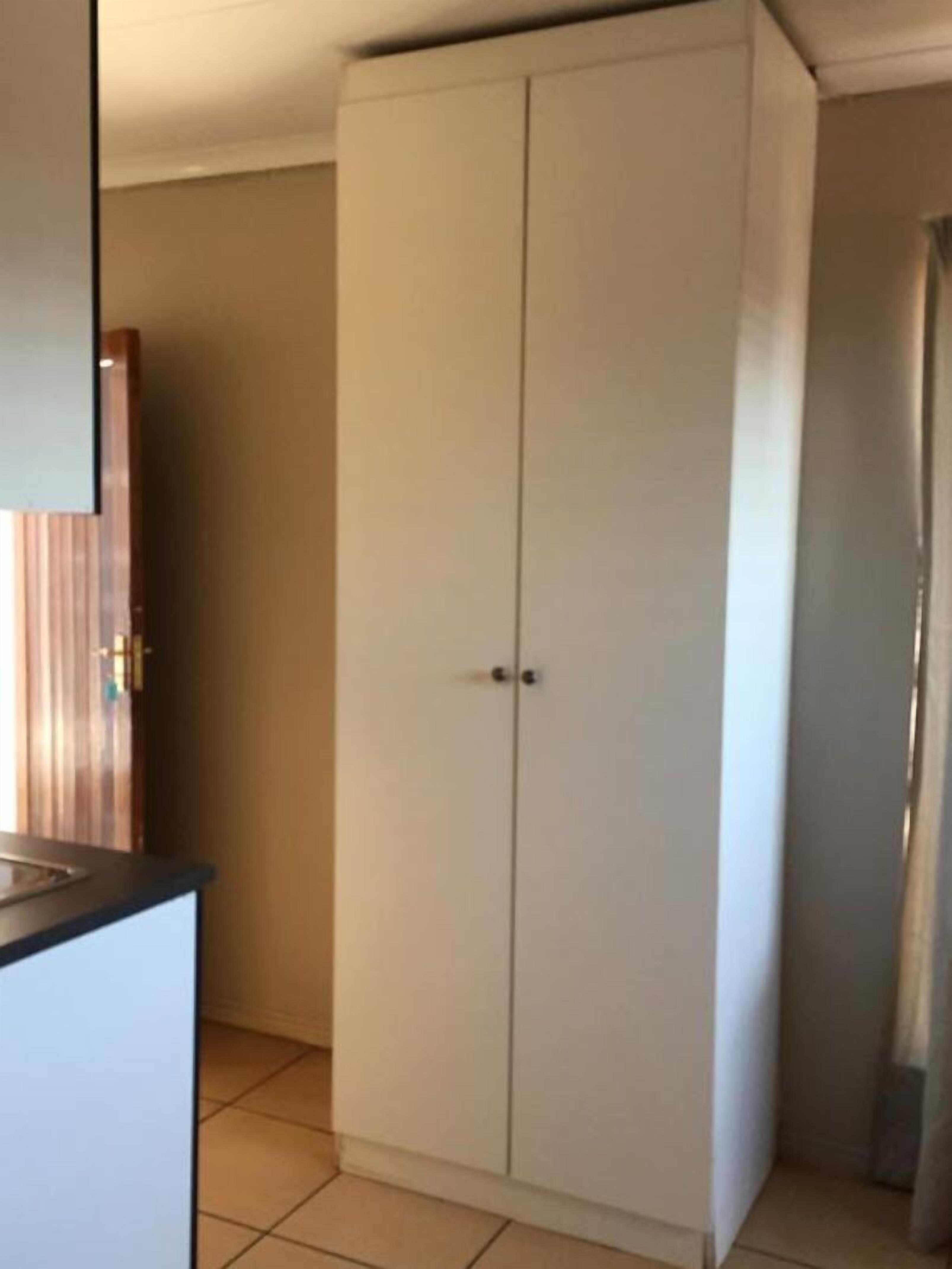 A room with a white wardrobe, a wooden door, and a tiled floor.