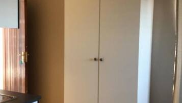A room with a white wardrobe, a wooden door, and a tiled floor.