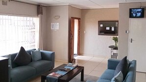 Una sala de estar con dos sofás, una mesa de centro y un televisor en la pared.
