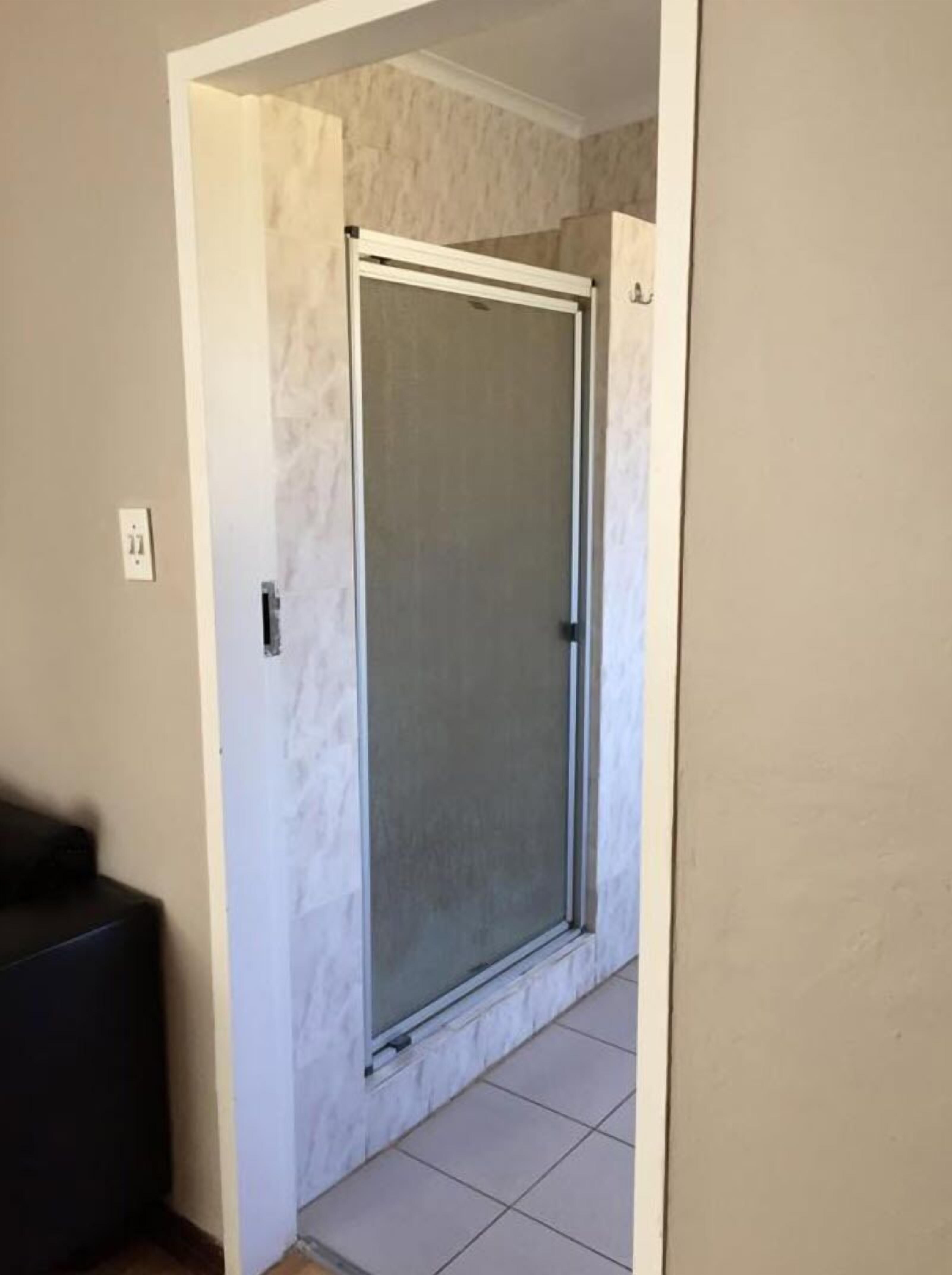 A hallway with a glass door leading to a room.