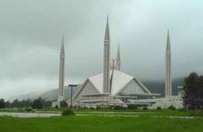 A large, modern building with a prominent central dome and four tall minarets.