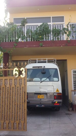 A white van parked at a gated entrance with the number 63. - Zaib Guest House (Islamabad)