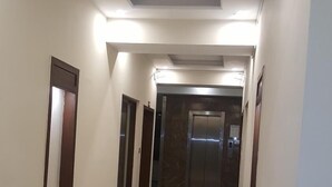 A hallway with a marble floor, wooden doors, and a central elevator.