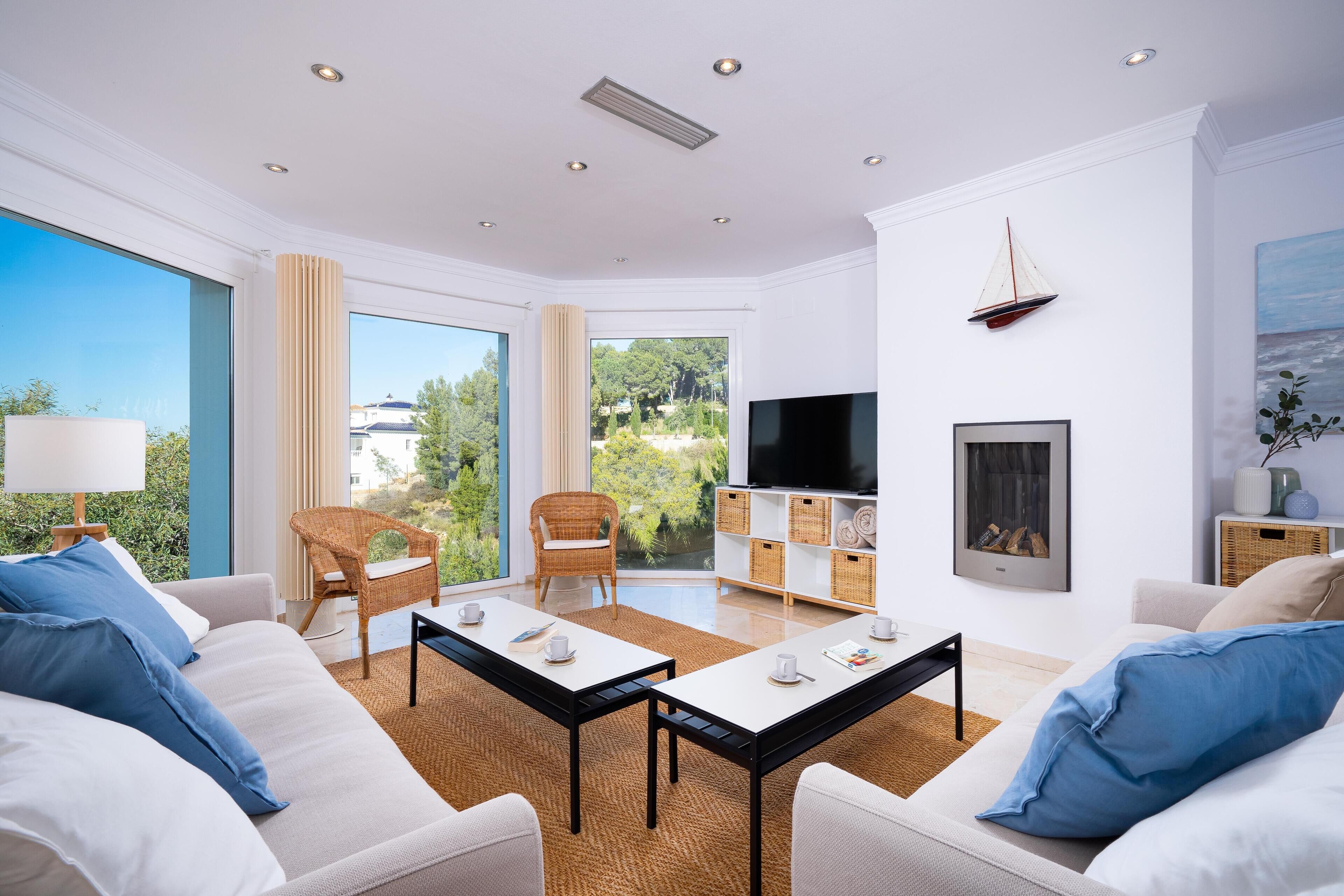 A modern living room with a sofa, two armchairs, a coffee table, a TV, and a fireplace.
