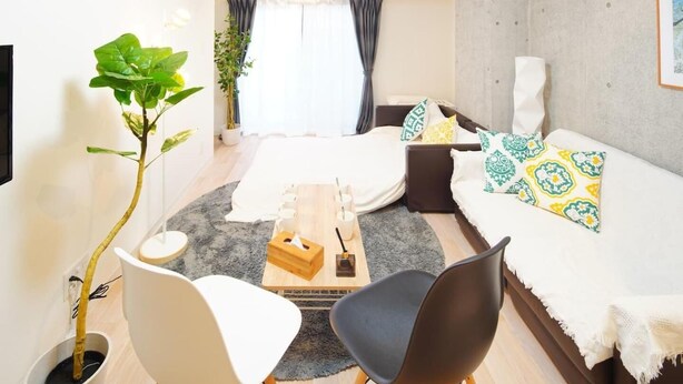 A modern hotel room with a bed, two sofas, a coffee table, a plant, and a TV. - Asakusa Hotel 201 (Tokyo)