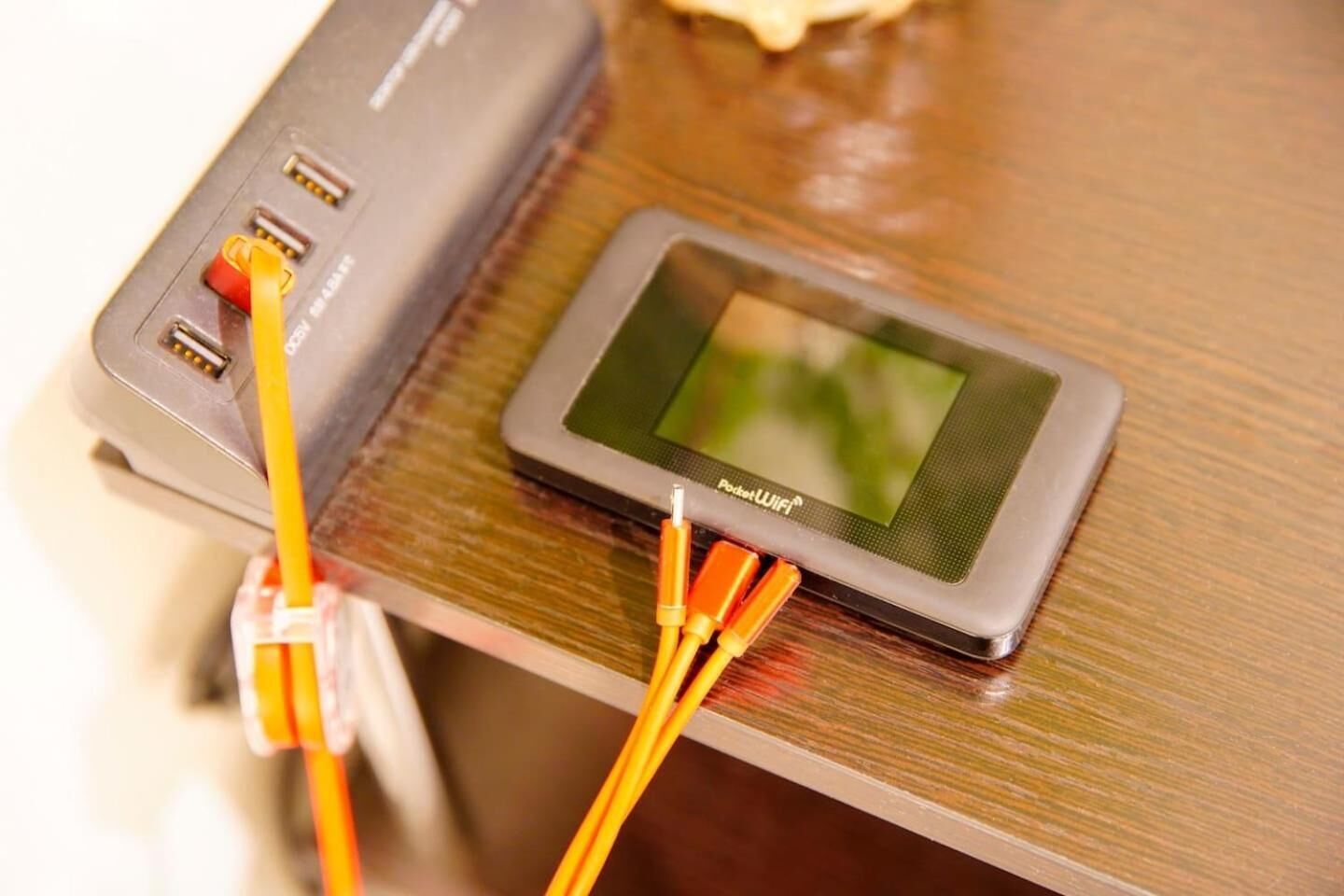 A portable Wi-Fi device with a screen and multiple Ethernet cables connected to it.
