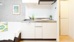 A compact kitchen with a sink, stove, and a small refrigerator. - Asakusa Hotel 201 (Tokyo)