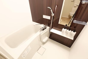 A bathroom with a bathtub, a shower, and a shelf with toiletries.