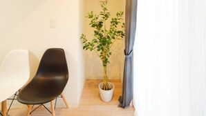 A room with a white wall, a black chair, a potted plant, and a grey curtain. - Asakusa Hotel 201 (Tokyo)