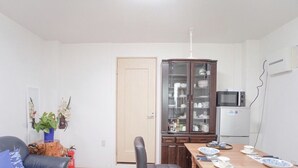 Ein Essbereich mit einem Holztisch, gedeckt für vier Personen, einem dunklen Ledersessel, einem Schrank mit Glastüren und einer Mikrowelle.