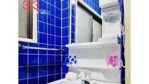 Ein Badezimmer mit einem weißen Waschbecken, blauen Fliesen, einem Spiegel und einem weißen Handtuchhalter.