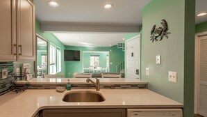 Una cocina moderna con un lavamanos de acero inoxidable, armarios blancos y una pared verde de acento.