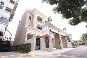 A multi-story residential building with a gated entrance, a signboard, and a visible balcony.