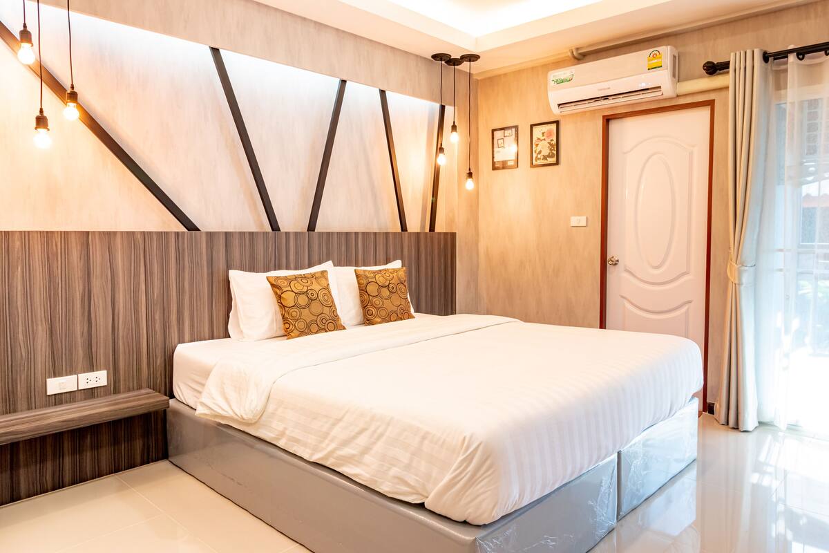 A modern bedroom with a large bed, wooden panel walls, and a built-in bench.