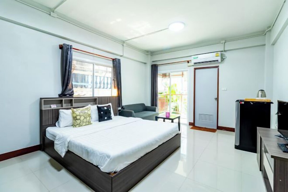 A hotel room with a bed, a desk, a chair, a wardrobe, and a balcony.