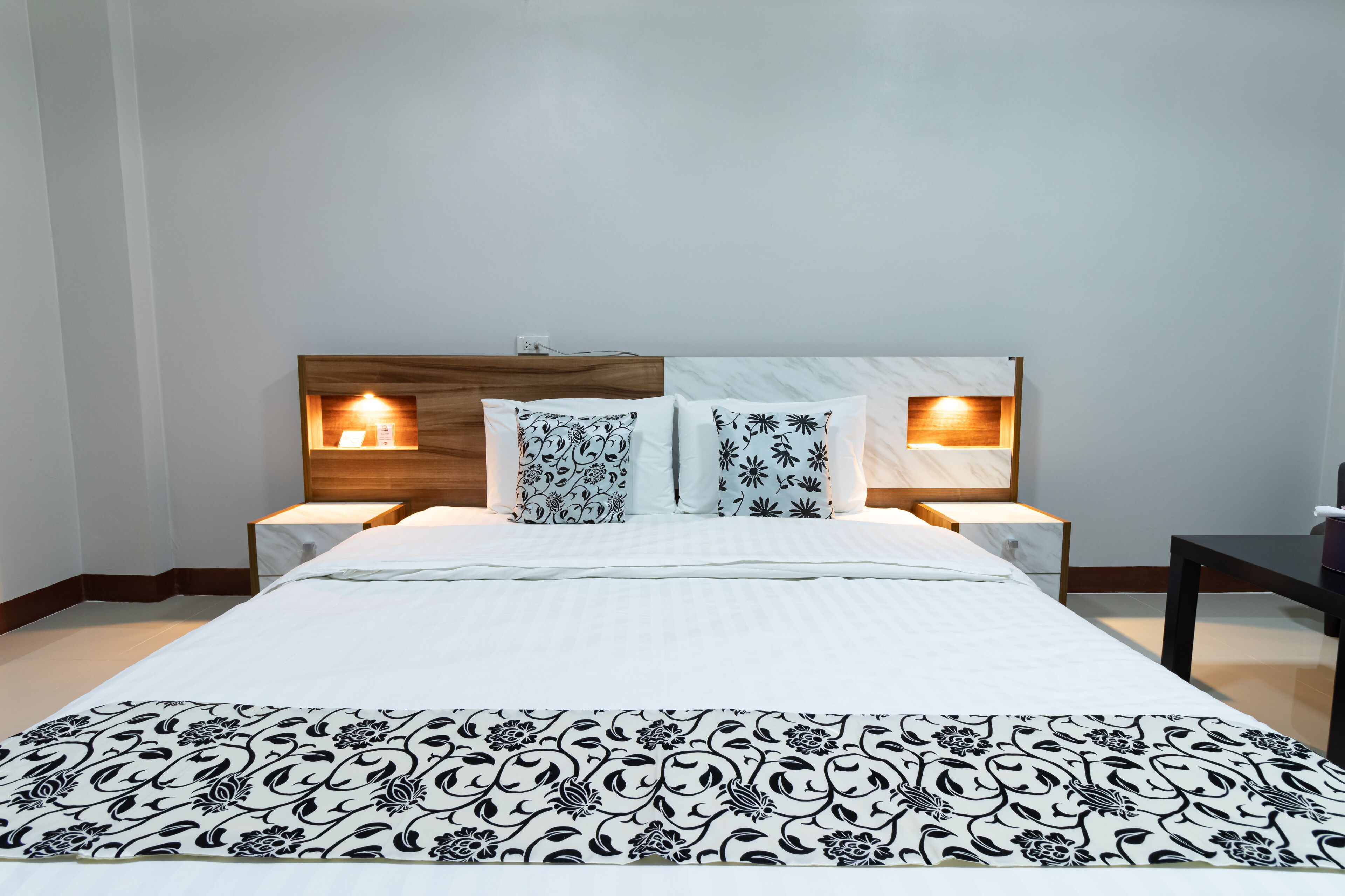 A hotel room with a large bed, two bedside tables with lamps, and a wooden headboard.