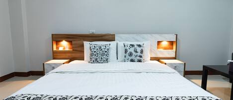 A hotel room with a large bed, two bedside tables with lamps, and a wooden headboard.