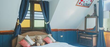 A bedroom with a bed, pillows, a teddy bear, a dresser, and a mirror.