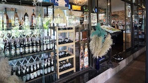 A storefront with various bottles of alcohol displayed in glass cases and shelves. - Baansuan Chomchun (Mae Taeng)