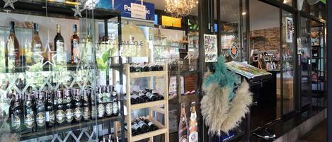 Une vitrine où sont exposées différentes bouteilles d’alcool, présentées dans des présentoirs et sur des étagères en verre.