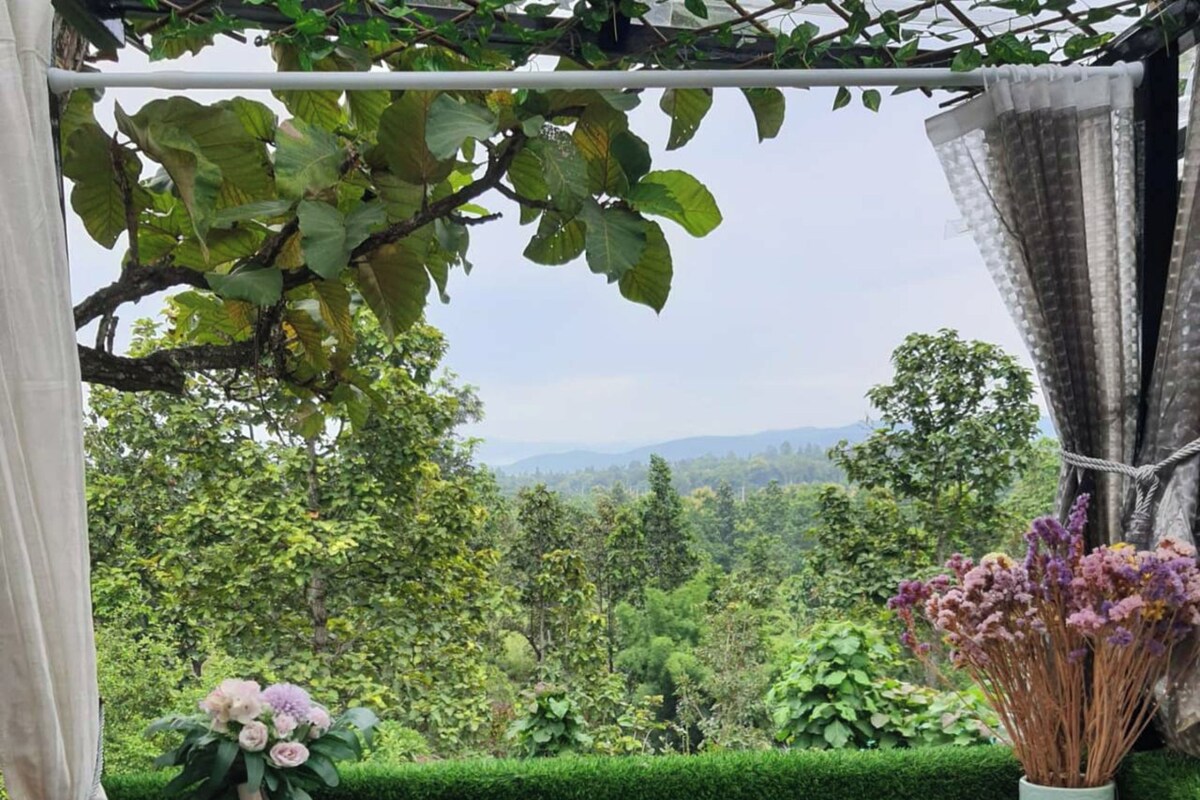 A terrace with a view of a lush green landscape, a table with a vase of flowers, and a decorative item on a tray.
