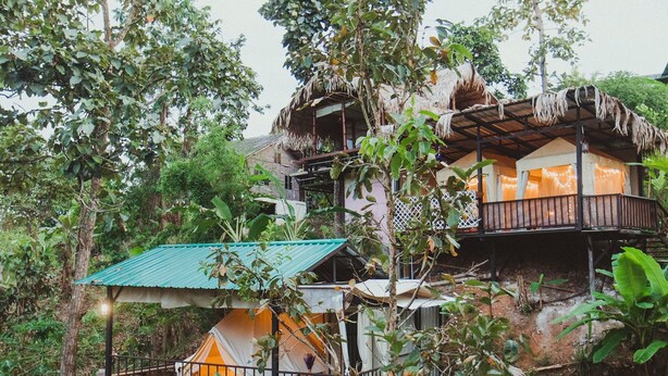 A treehouse-style accommodation with multiple levels, surrounded by dense foliage. - Baansuan Chomchun (Mae Taeng)