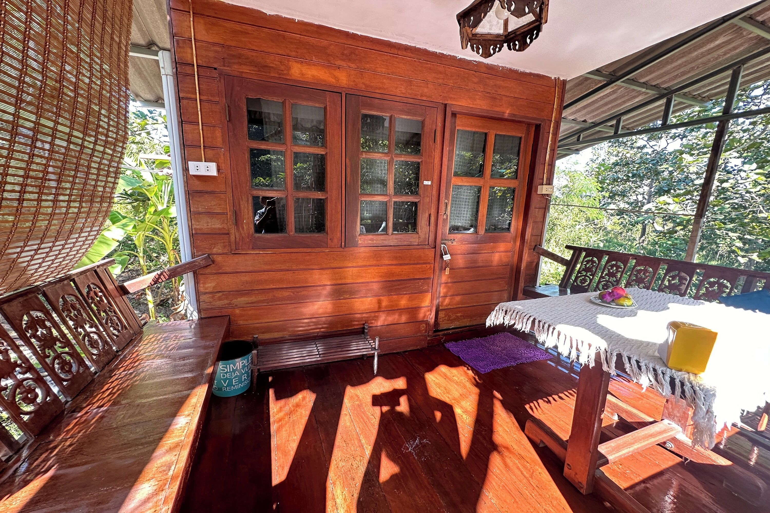 Una habitación de madera con un ventanal grande, una mesita con un cojín y un banco.