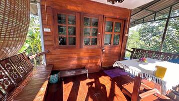 Una habitación de madera con un ventanal grande, una mesita con un cojín y un banco.