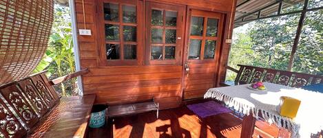 A wooden room with a large window, a small table with a cushion, and a bench.