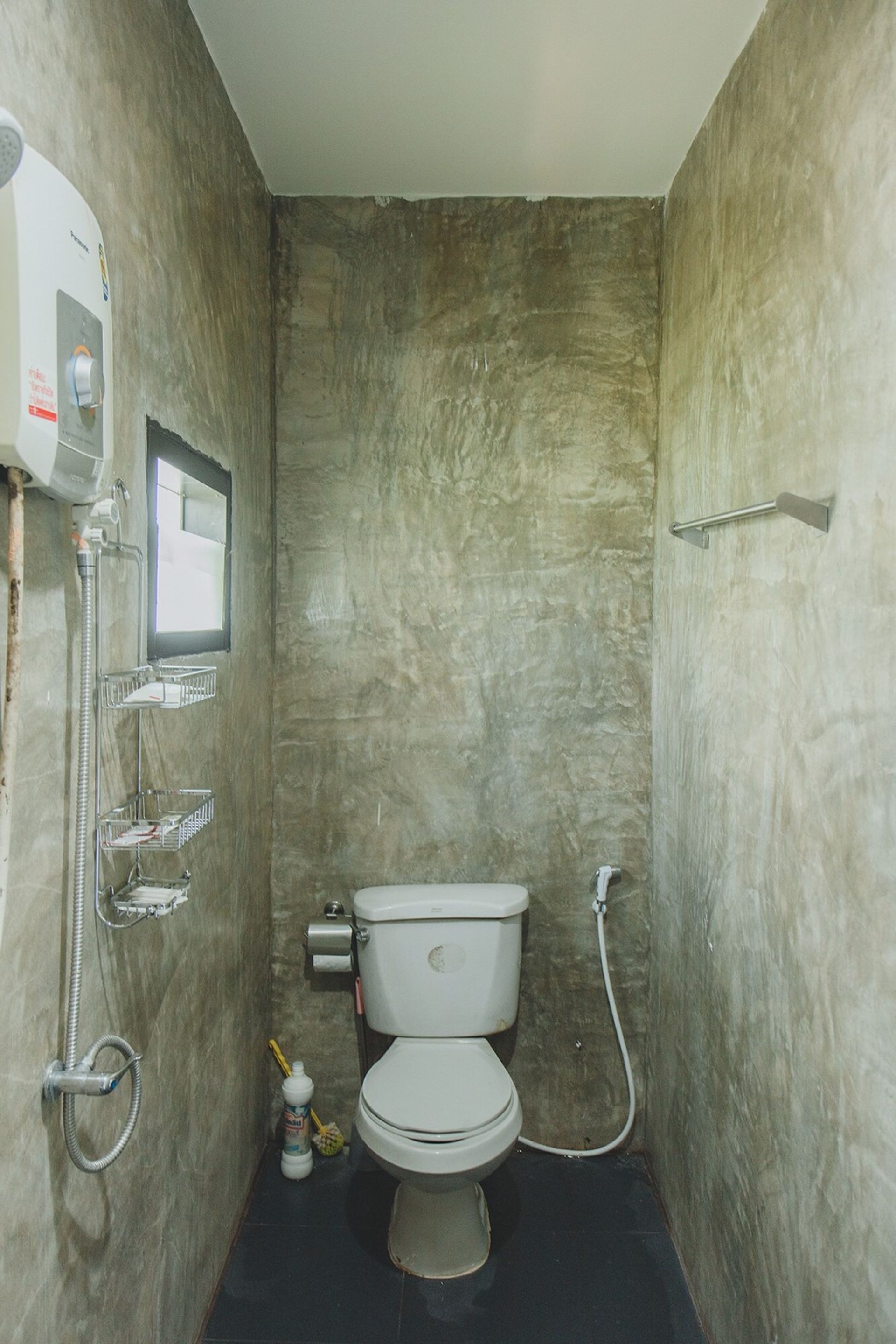 Un baño pequeño con inodoro, ducha y secador de manos.