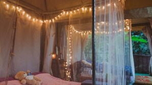 A room with a bed, a teddy bear, and string lights. - Baansuan Chomchun (Mae Taeng)