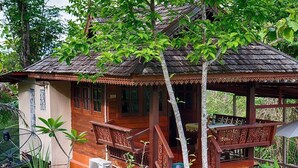 A wooden house with a porch, surrounded by greenery. - Baansuan Chomchun (Mae Taeng)