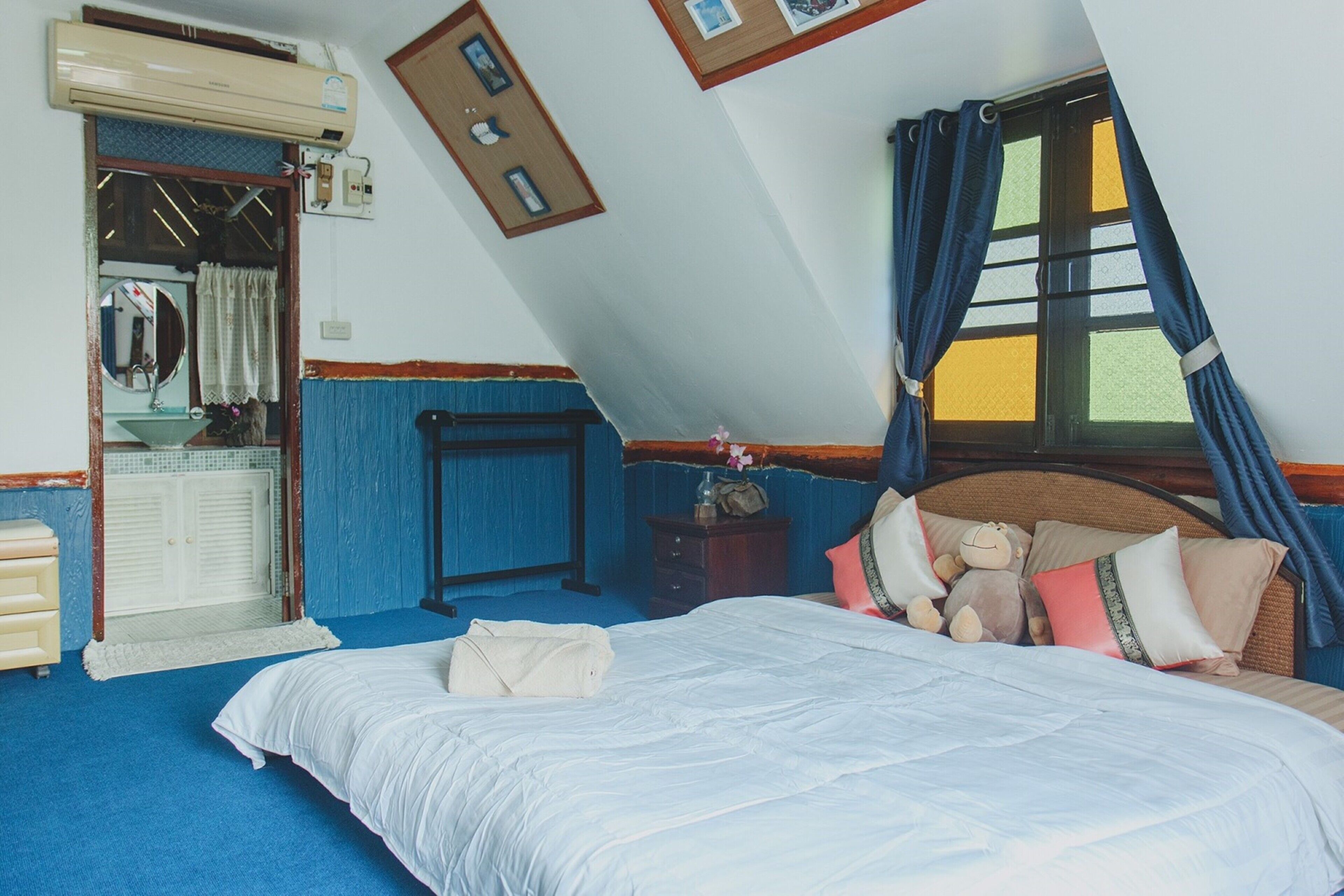 Un dormitorio con cama, cómoda, espejo y ventana con cortinas.