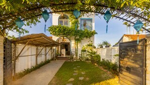 A courtyard with a covered walkway, a wooden gate, and a building with a balcony. - Lua House (Da Nang)