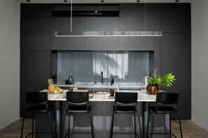 A modern kitchen with a central island, black chairs, and a large window. - Good Story Village (Ahangama)
