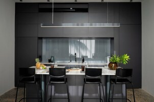 Una cocina moderna con una isla central, sillas negras y un ventanal grande.