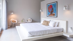 A modern bedroom with a large bed, bedside tables, a small table, and a chair. - Good Story Village (Ahangama)