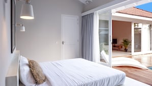 A bedroom with a bed, a large window, and a view of a pool and outdoor seating area. - Good Story Village (Ahangama)
