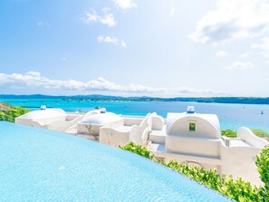 A poolside view with a clear blue sky, a calm sea, and white buildings with domed roofs. - Yuki Suite Kourijima (Nakijin)
