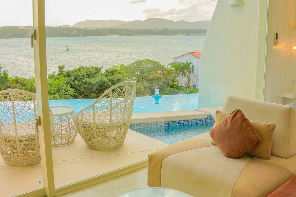 Quarto com vista para uma piscina e um corpo de água.