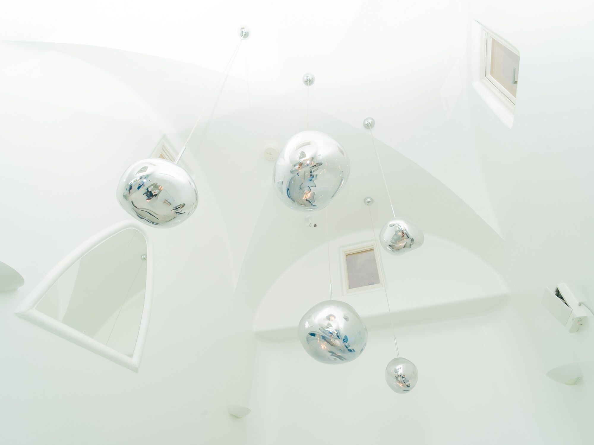 A modern interior with spherical mirrors on the ceiling and a skylight.