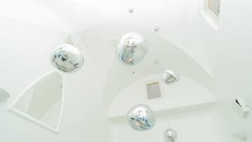 A modern interior with spherical mirrors on the ceiling and a skylight.