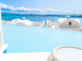 Zona de piscina con estructuras blancas en forma de cúpula y vistas al mar y colinas.