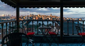 A balcony with chairs and a table, overlooking a cityscape with buildings and a river. - Astra Boutique Hotel (Istanbul)