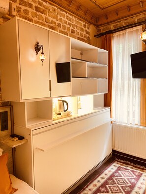 A compact kitchen with white cabinets, a built-in stove, and a window with curtains.